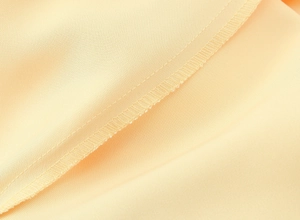 Vue détaillée du tissu satiné jaune clair montrant la texture lisse et les coutures plates