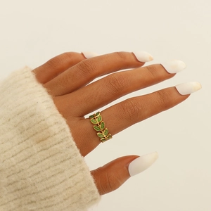 Close-up of gold-plated leaf ring with green enamel on a model's finger