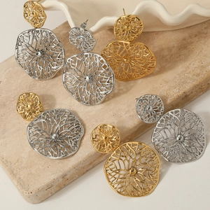 Hollow cutout flower metal earrings in gold and silver finish on stone display