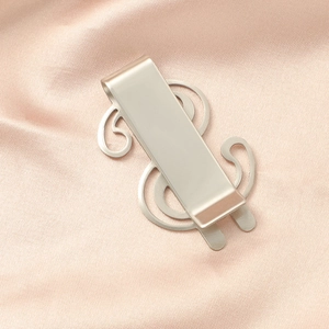 Close-up of a silver dollar sign money clip made of brushed stainless steel on pink silk
