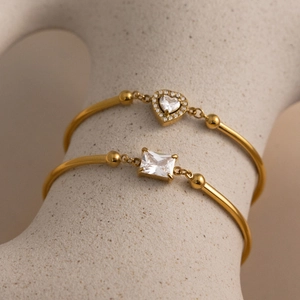 Detail of 18K gold plated bracelets with heart and rectangle zircon stones on a stand