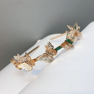 Detailed view of hollow gold butterfly charms on a metallic headband for women