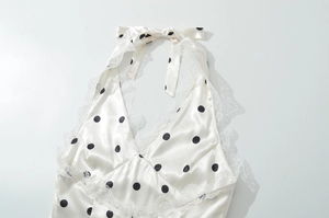 Flat lay of cream satin halter top with black polka dots and fine lace trim detailing