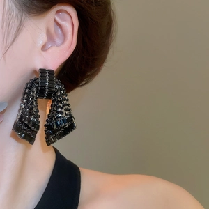Close-up of black rhinestone bow earrings worn by a model showing the elegant drop