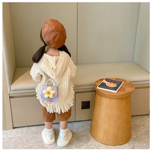 Girl wearing purple mini bag with large yellow plush flower and pearl handle strap