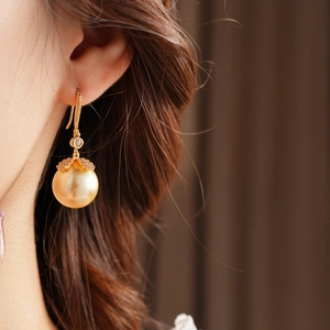Gros plan d'élégantes boucles d'oreilles perles dorées avec fleur en zircon sur un mannequin