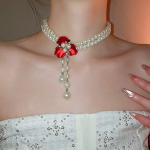 Detail of double-strand pearl choker featuring a red crystal flower pendant with fringe