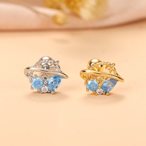 Gros plan des boucles d'oreilles planète avec zircons bleus en finitions argent et or