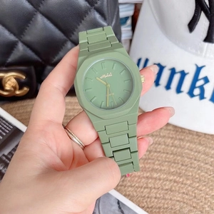 Detail of green silicone women's quartz watch held against a stylish lifestyle background