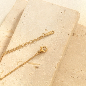 Detailed view of golden stainless steel necklace with lobster clasp and S.Steel logo tag