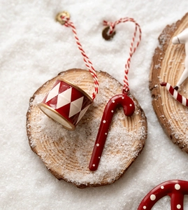 Close-up of Nordic Christmas drum and candy cane ornaments on rustic snowy wood slice