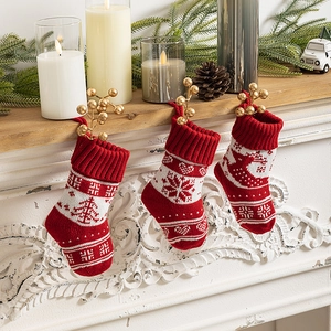 Set of 3 knitted red and white Christmas stockings with reindeer patterns on white fireplace