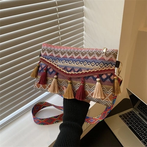 Detail of bohemian knitted crossbody bag with colorful tassels and ethnic pattern strap