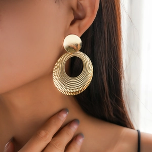 Detailed view of large gold hollow geometric hoop earring with radial textured surface