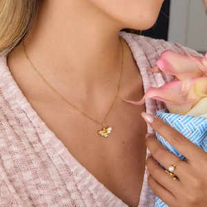 Detail von Bienenkette und Perlenring an Model mit weichem Licht und Blumendekor