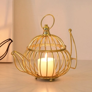 Nordic gold birdcage teapot candle holder with a lit candle for elegant home decor