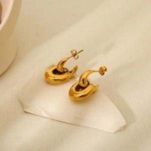 Detailed macro view of 18K gold-plated U-shaped stainless steel earrings on white stones