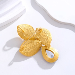 Elegant gold leaf brooch with textured metal leaves and a clear teardrop crystal