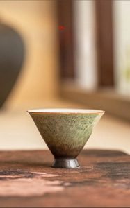 Macro detail of kiln-turned ceramic tea cup with green starry glaze and white interior