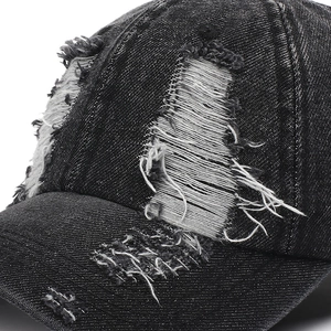 Distressed black denim baseball cap with vintage frayed holes and a wide brim for street style