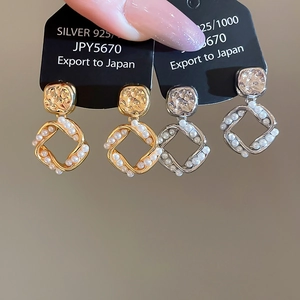 Detail of 925 silver square earrings with hammered gold finish and pearl borders