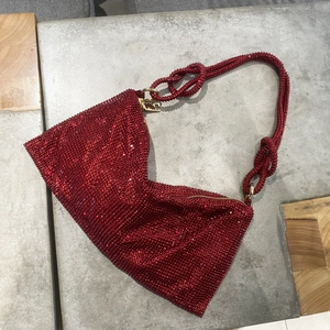 Macro detail of luxury red rhinestone handbag with knotted strap and gold zipper