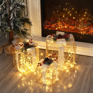 Close-up of warm LED lighted Christmas gift boxes with pine cones and silver bows