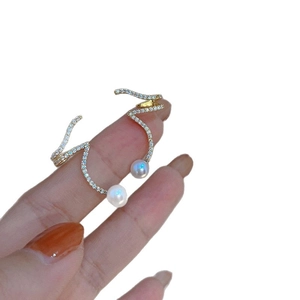 Elegant gold spiral crawler earrings with sparkling diamonds and white pearls on hand