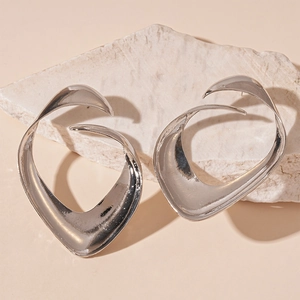 Detailed shot of silver irregular geometric metal earrings on a natural stone base
