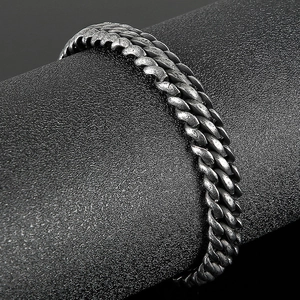 Macro shot of retro stainless steel mesh bracelet with oxidized finish on black cylinder