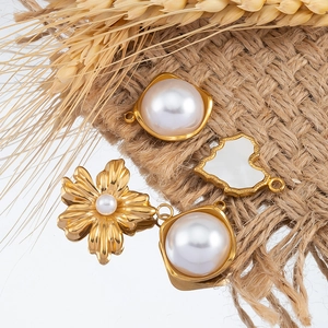 Detailed view of floral and heart-shaped gold pendants with pearls on rustic linen
