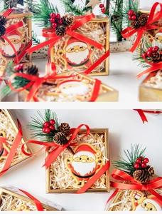 Detail view of Santa Claus cookie in a PVC gift box with red ribbon and pine cone accents