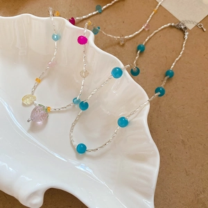 Dettaglio del ciondolo a fragola in vetro e perline colorate su collana a catena argento