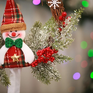 Close-up of snowman wreath with red plaid fabric, pine needles, and red berries