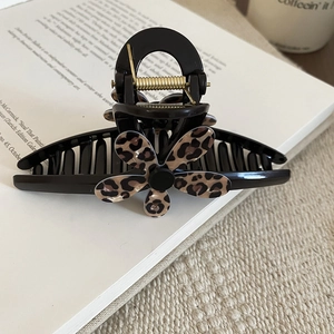 Detailed view of leopard print lace hair claw clip with golden metal spring on book