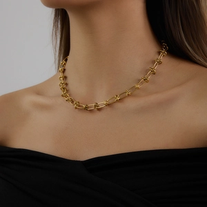 Gros plan d'un collier à maillons ovales plaqué or 18 carats porté par un mannequin