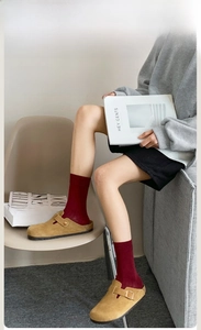 Detail shot of ribbed deep red cotton socks paired with mustard suede mule clogs