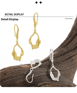 Close-up of irregular lava textured earrings in gold and silver hanging on wood