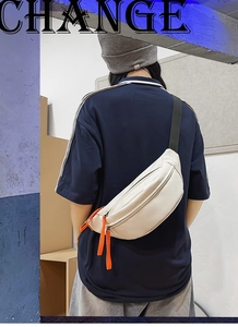 Detail of off-white leather chest bag featuring vibrant orange zipper pulls for casual style