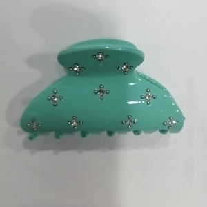 Detail of mint green shark hair claw clip with star-shaped sparkling rhinestone accents