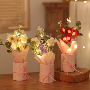 Three handmade crochet flower bouquets in pink pots with warm LED fairy lights