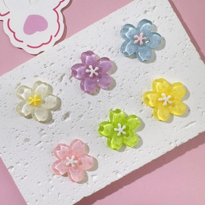 Macro view of six colorful translucent resin cherry blossom charms on textured stone
