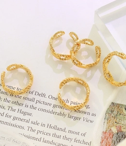 Detail of five 18K gold plated twisted chain rings on decorative aesthetic books