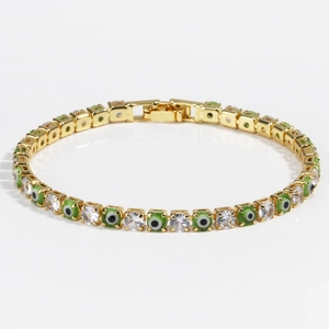 Detail of gold tennis chain bracelet with green evil eye accents and zircon stones