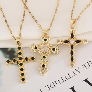 Three gold cross necklaces with black and clear zircons on elegant white fabric background