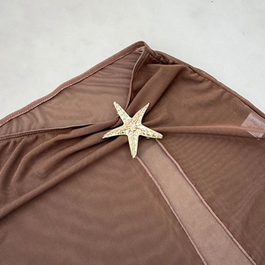 Detail of sheer brown mesh fabric featuring a textured gold starfish metal ornament