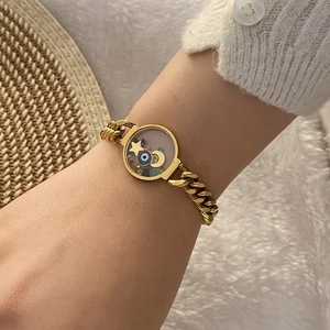 Gold chain bracelet featuring evil eye and celestial charms with colorful stones