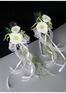 Detail of white artificial roses and organza ribbons on wedding champagne glasses