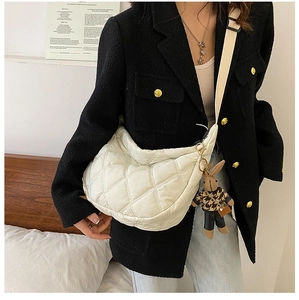 Close-up of white quilted dumpling bag with cute bunny pendant and woven strap