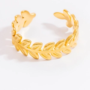 Detailed macro shot of golden stainless steel open ring with olive leaf pattern texture
